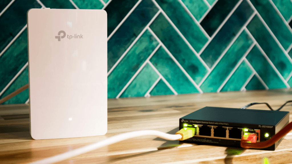 Wi-Fi router and network switch connected with cables on a table.