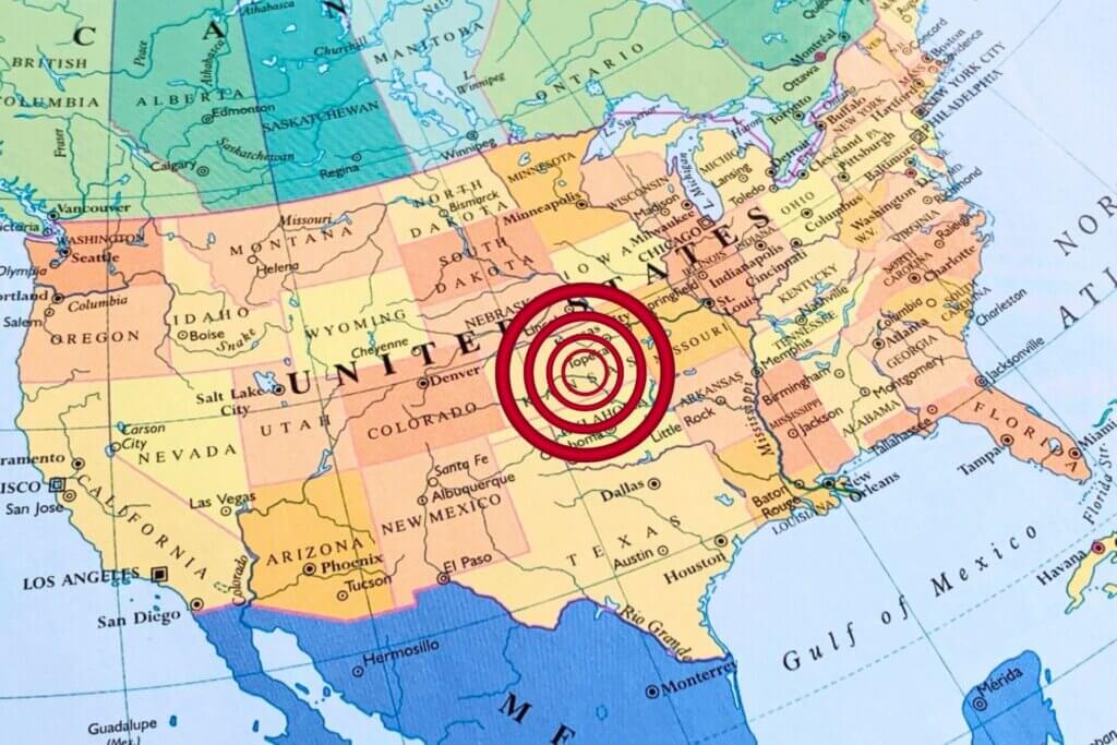 Map of the United States with a red target marker centered over Kansas, illustrating earthquake activity in the U.S. heartland.