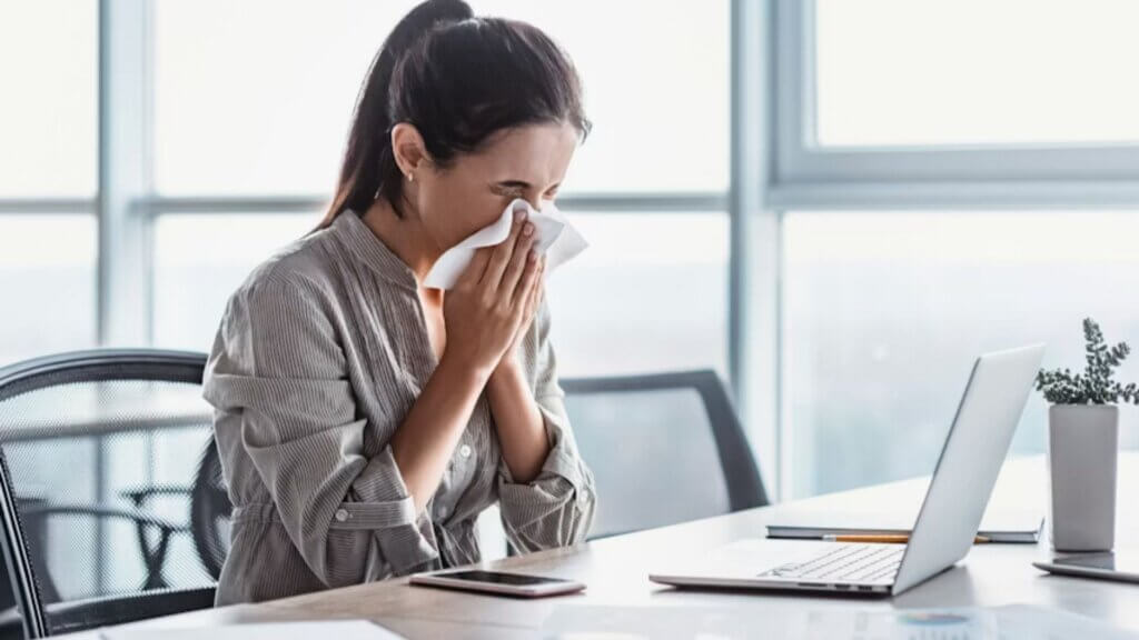 Person feeling sick at work in front of a computer at the office.