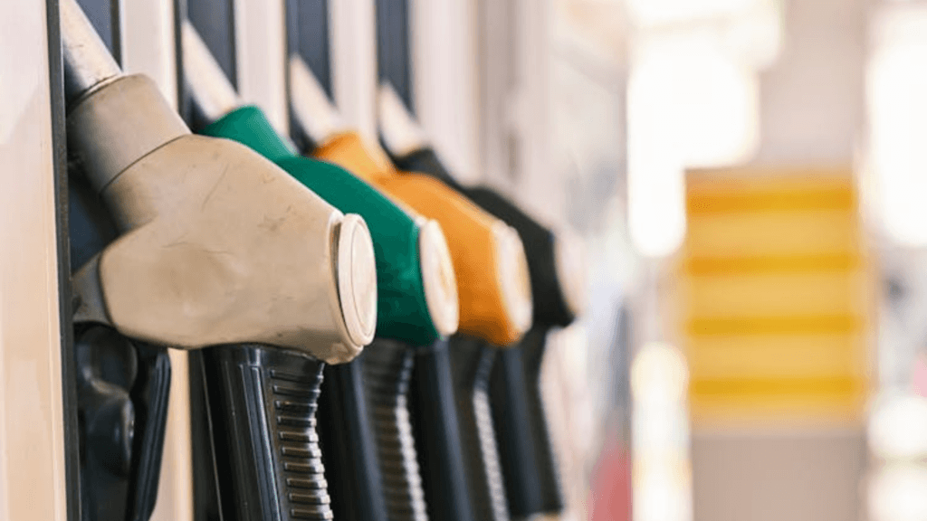A row of different colored fuel nozzles (grey, green, and orange) at a gas station pump.