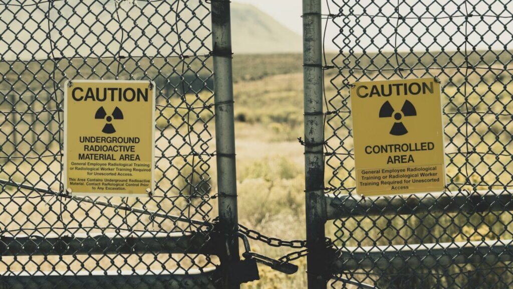 Yellow radiation caution signs on a chained chain link fence outdoors.
