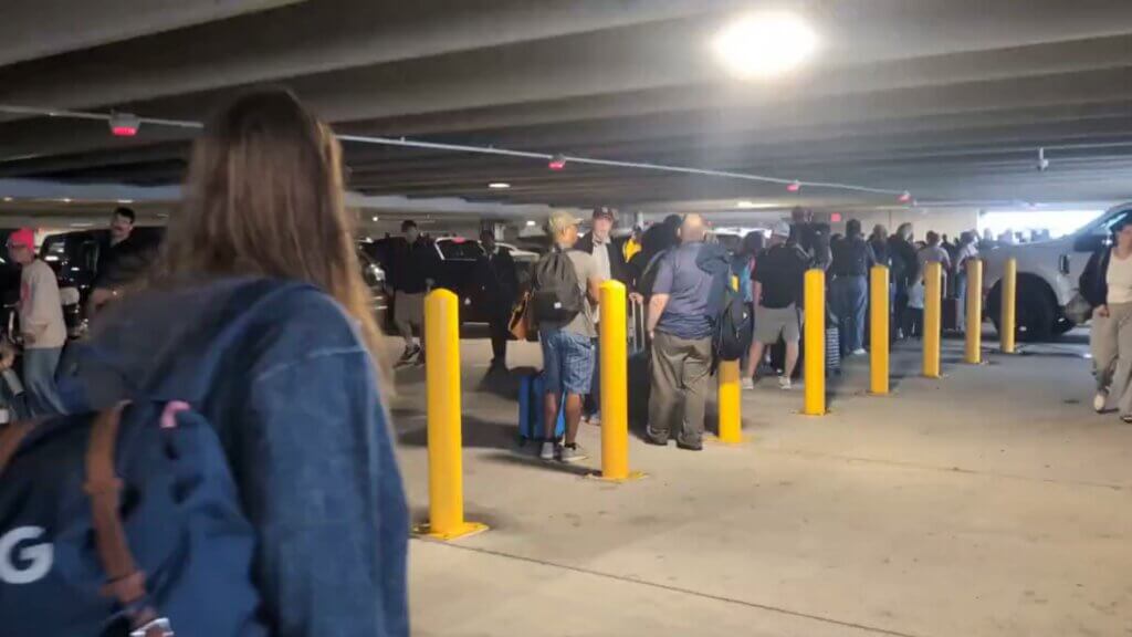 A screenshot from a video posted by @AubryKWDSU on X, showing the line stretching into the parking garage.