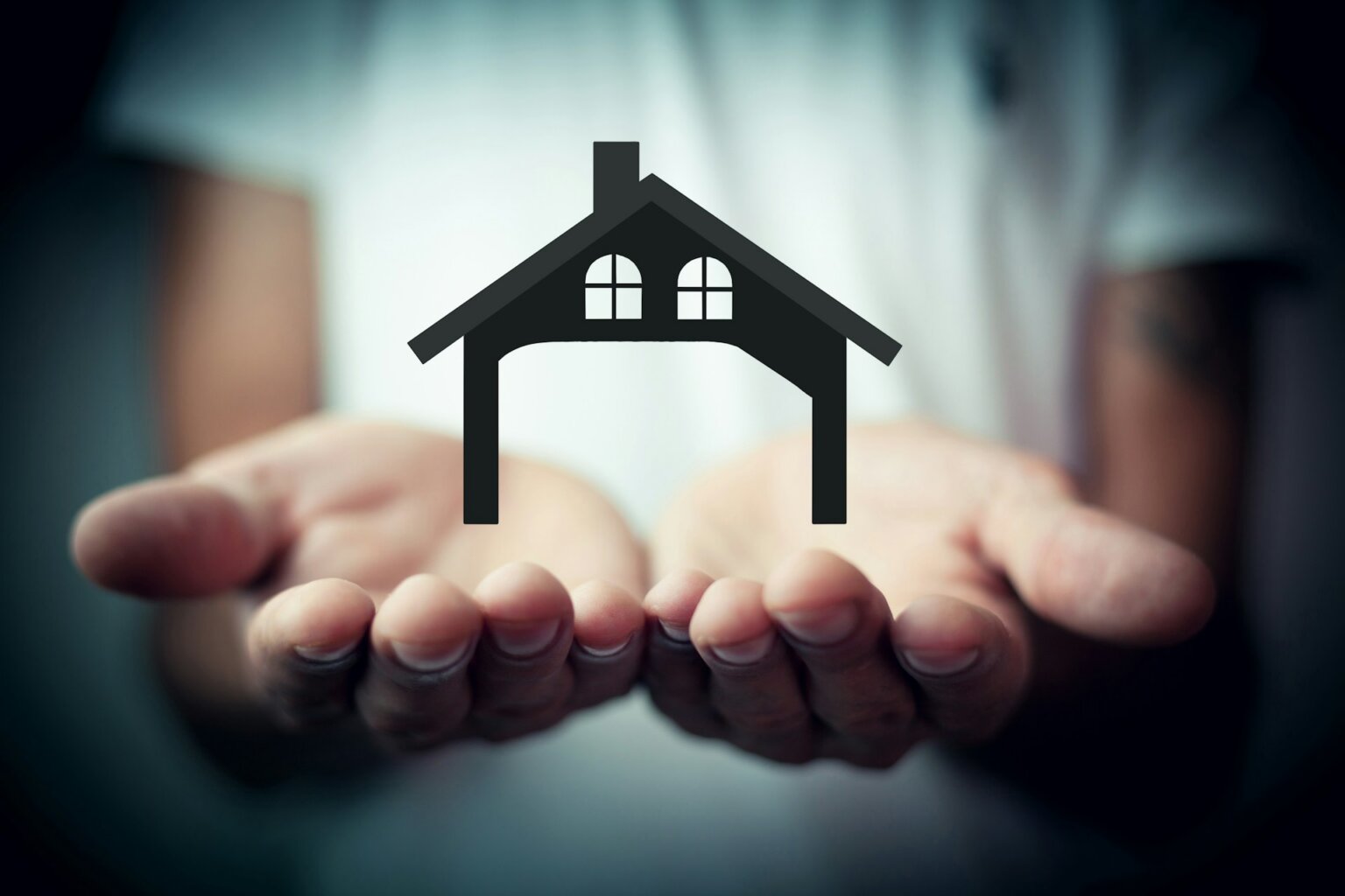 House icon hovering above open hands symbolizing homeownership and rising mortgage costs.