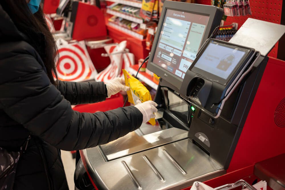 Shopper scanning packaged item at a Target self-checkout kiosk inside the store.