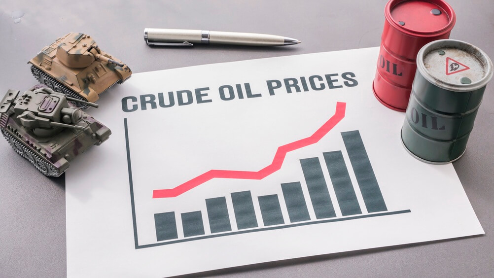 Chart showing rising crude oil prices with miniature oil barrels and military tank models on a table.