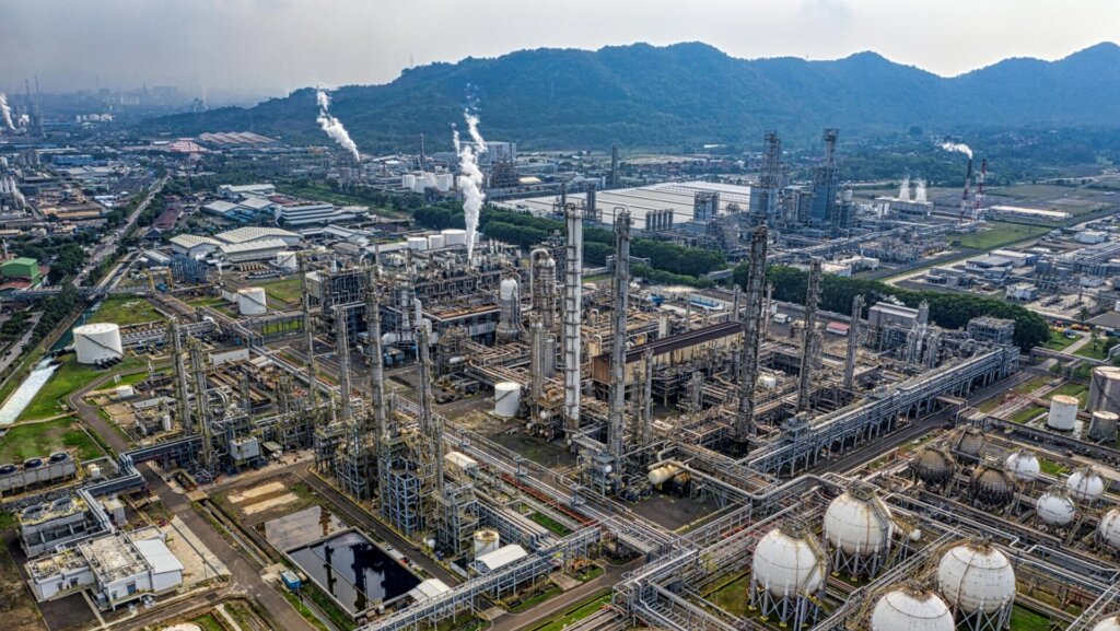 Industrial plant with smokestacks and pipelines in large refinery complex.