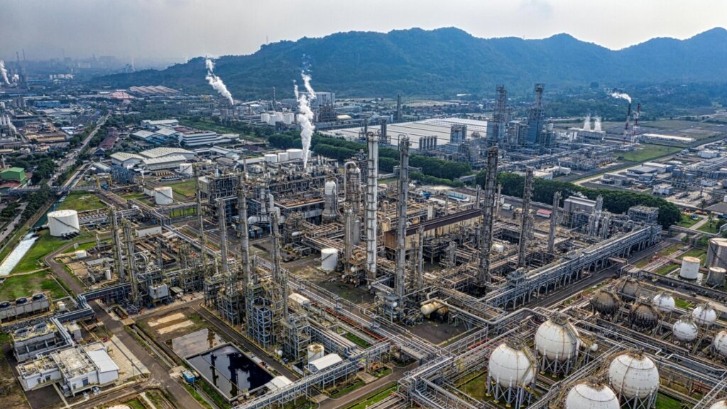 Industrial plant with smokestacks and pipelines in large refinery complex.