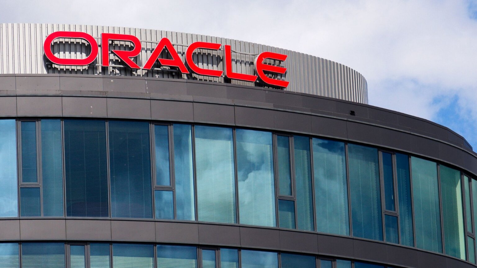 Oracle Lays Off 30,000 Workers via Email ‘Without Prior Notice’ as Company Shifts Focus to AI Oracle logo displayed on the exterior of a company office building.