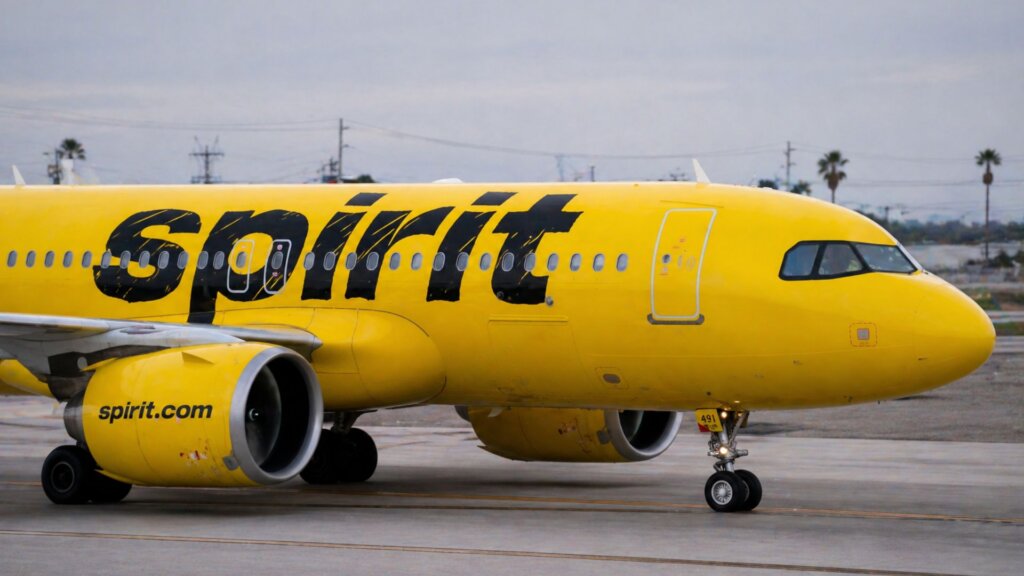 Bright yellow Spirit Airlines plane parked on a runway with the bold black “spirit” logo across the side.