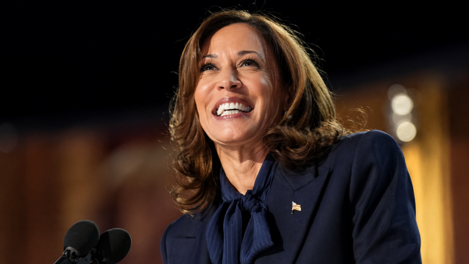 Kamala Harris smiling while speaking at a podium during a public event.