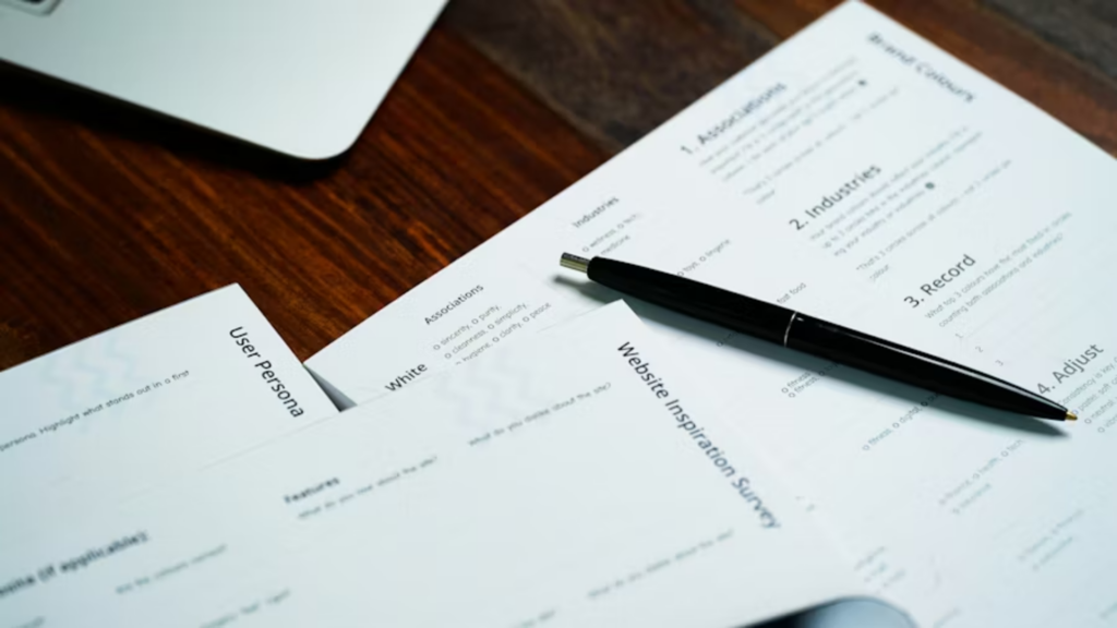A top-down shot of several business documents on a wooden desk.
