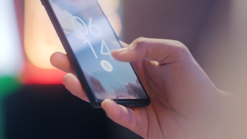 A close-up view shows a hand holding and unlocking a smartphone.