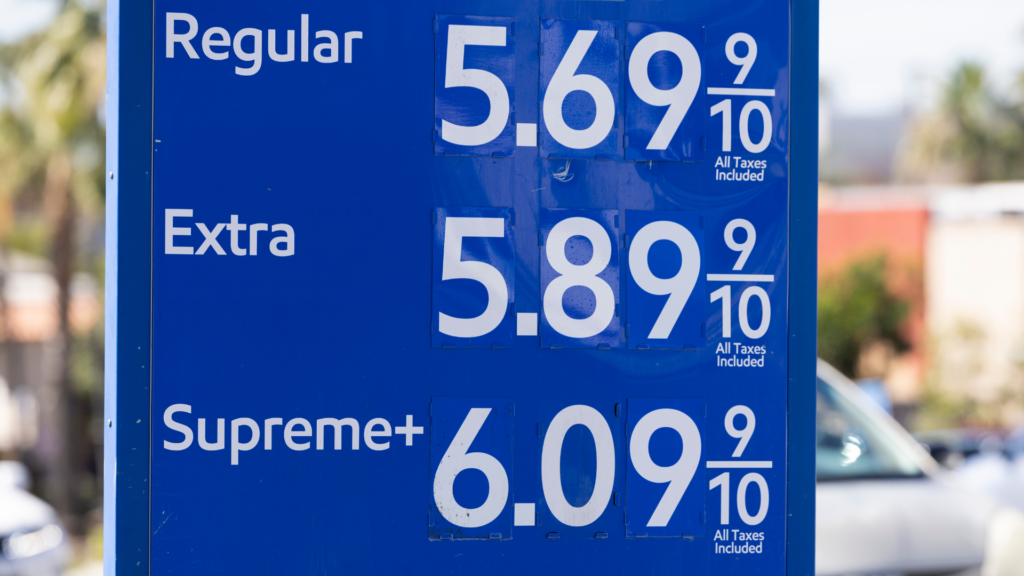 A blue gas station sign displays high fuel prices.