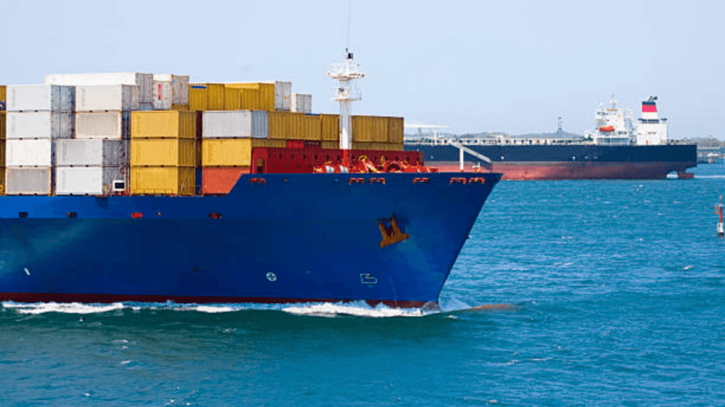 A massive blue container ship carrying hundreds of colorful shipping containers.