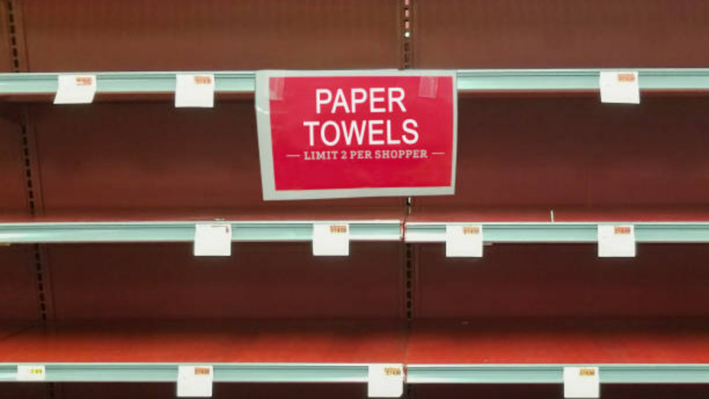 An eye-level shot of several empty metal grocery store shelves.