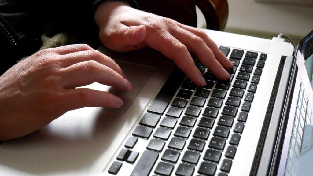 Hands typing on a laptop keyboard, representing an employee receiving an email notice.