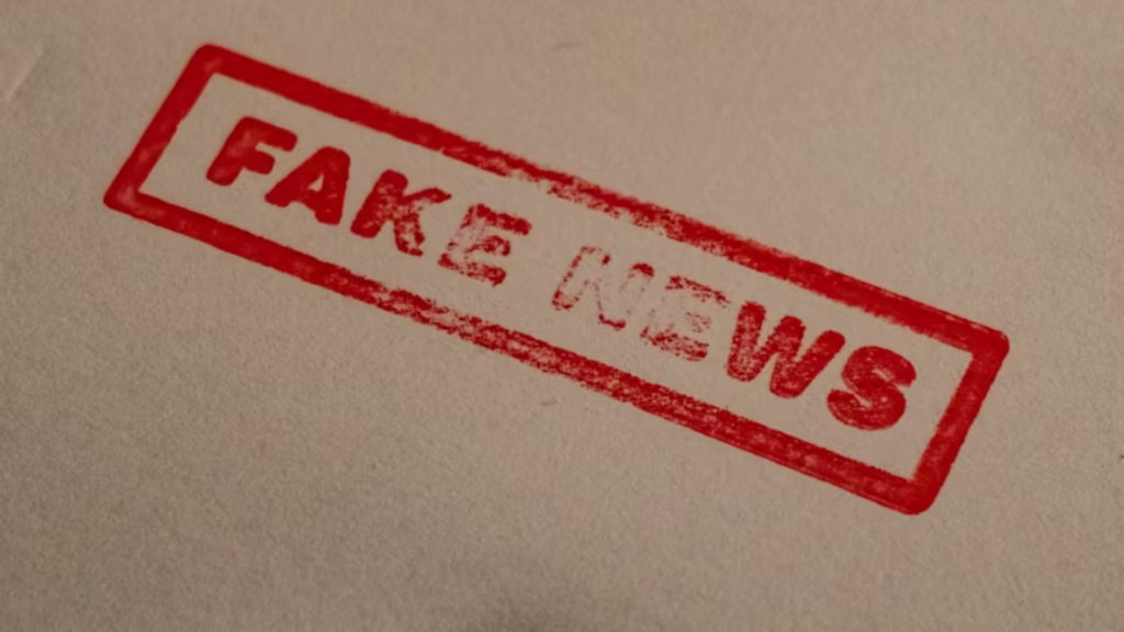 A close-up of a red rectangular stamp on a piece of off-white paper that reads "FAKE NEWS" in a distressed, weathered font, symbolizing misinformation or hoaxes.