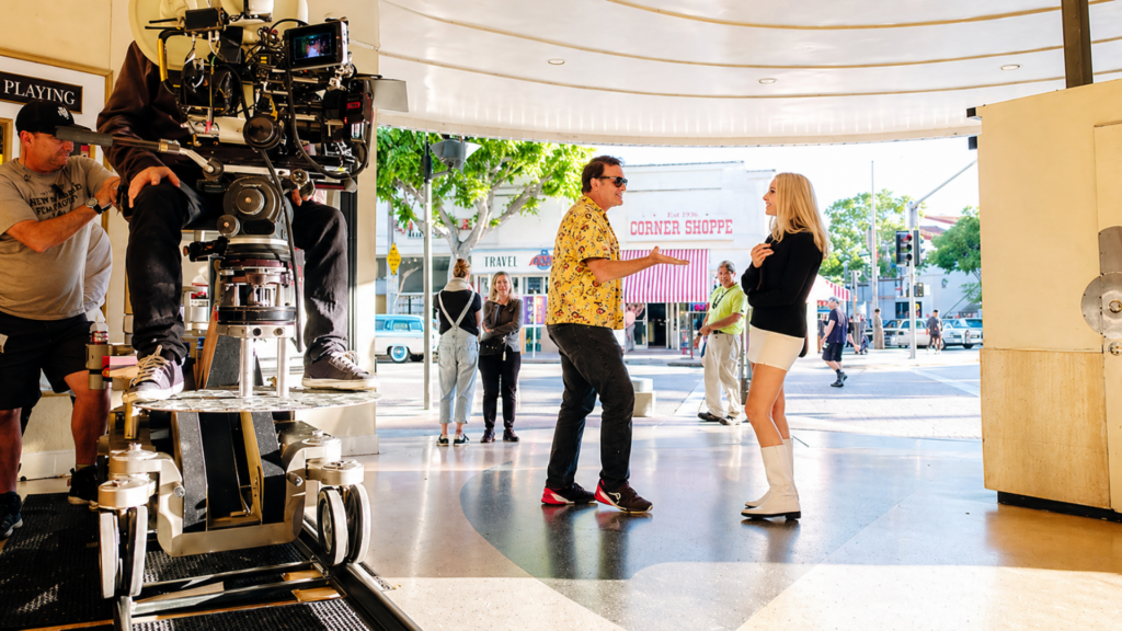 Film crew operates camera while Quentin Tarantino and Margot Robbie talk on the set of Once Upon a Time In Hollywood.