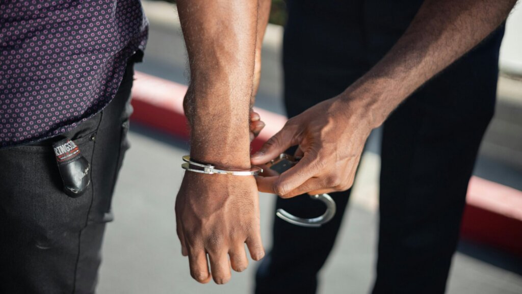 Person with hands cuffed behind their back during an arrest.