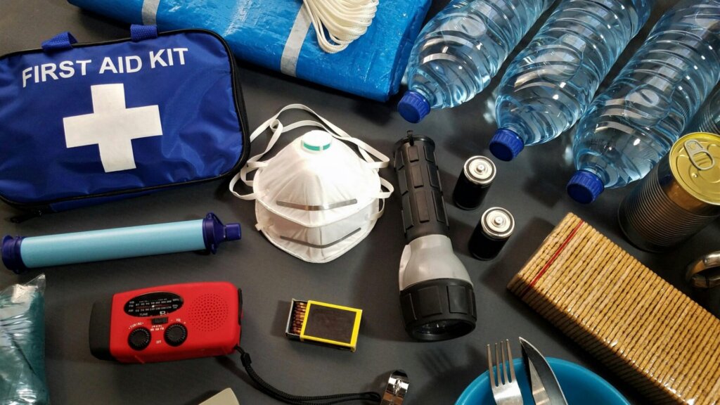 Emergency preparedness kit with supplies including flashlight, mask, and bottled water.