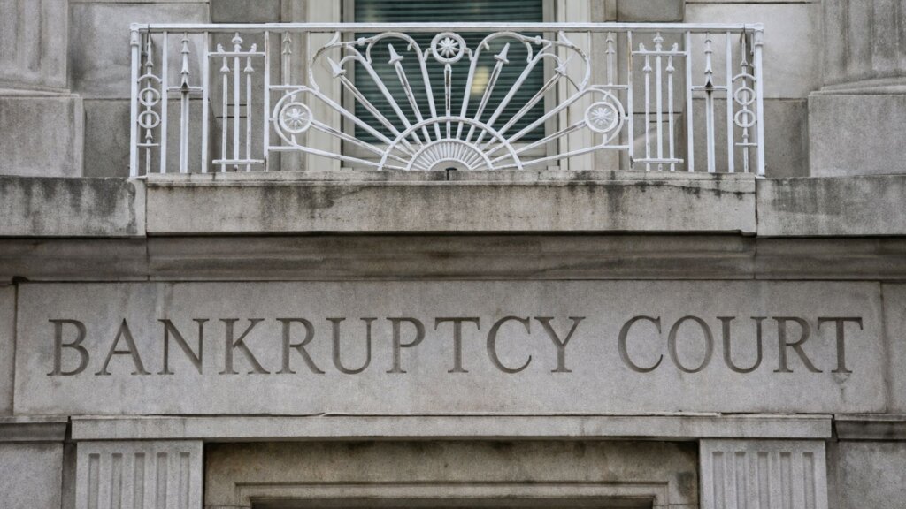 Stone building facade engraved with the words “BANKRUPTCY COURT” beneath a decorative white railing and window.