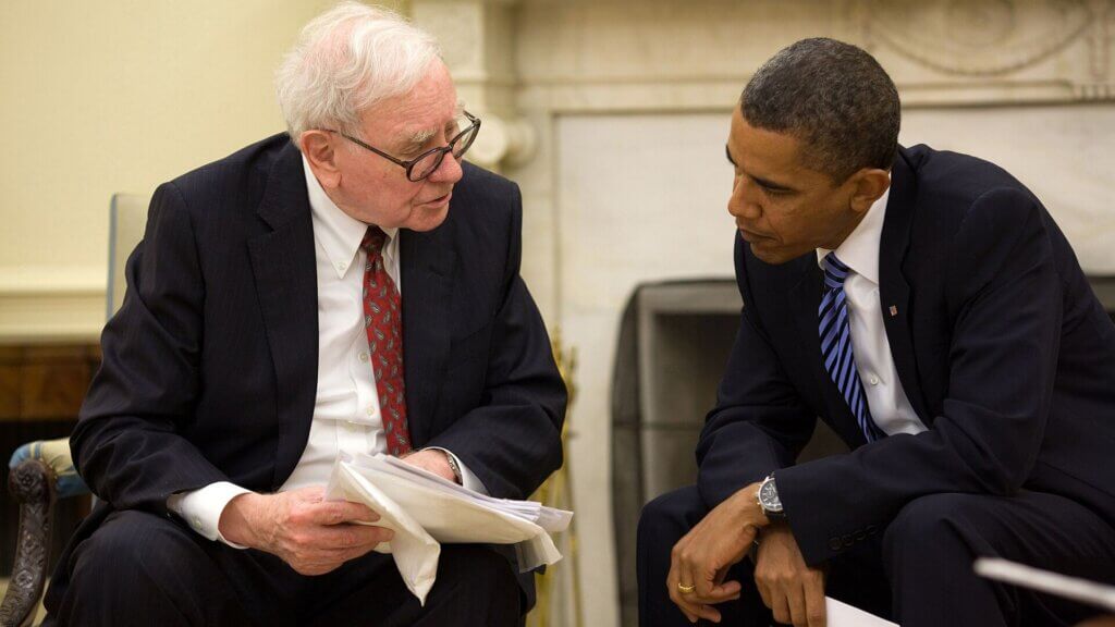 Warren Buffett and President Barack Obama seated and reviewing documents during a meeting.