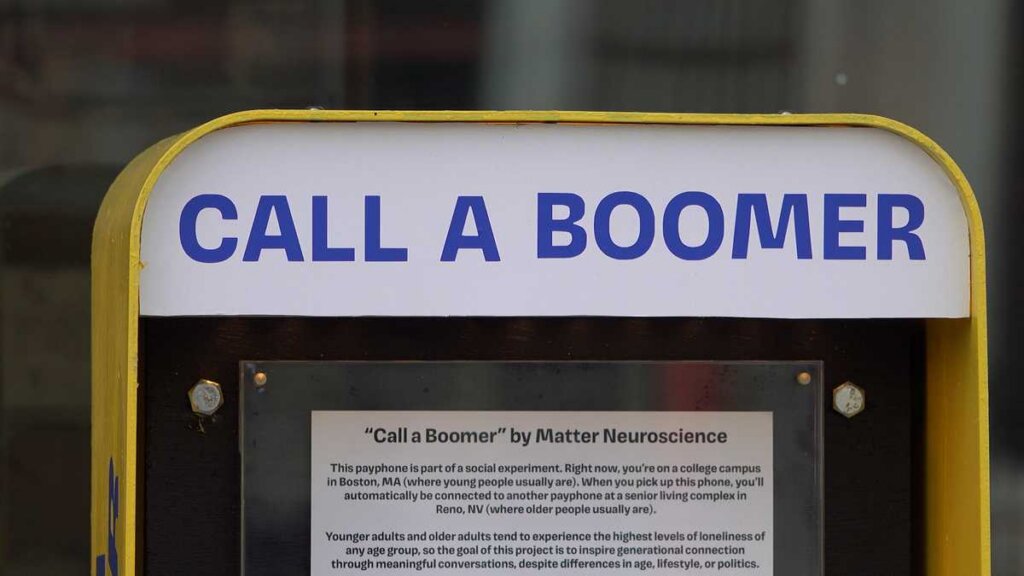 Sign reading “Call a Boomer” displayed on a public payphone.