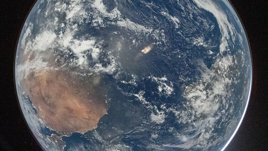 A full view of Earth from space reveals swirling white clouds over deep blue oceans and the brown landmass of Australia.