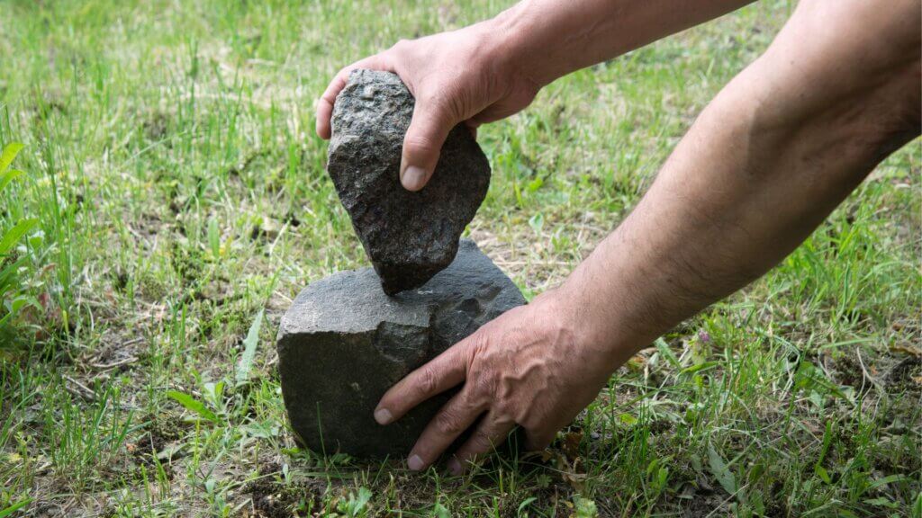 Man with two stones in hands and hitting the two stones against each other.