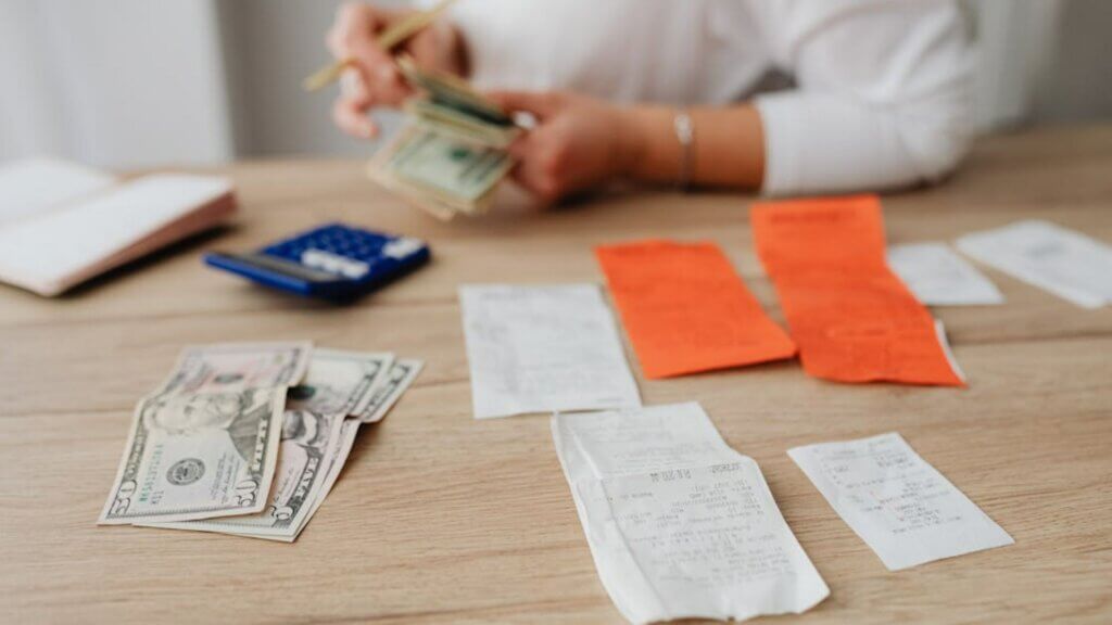 Person counting cash at a desk with receipts and a calculator.