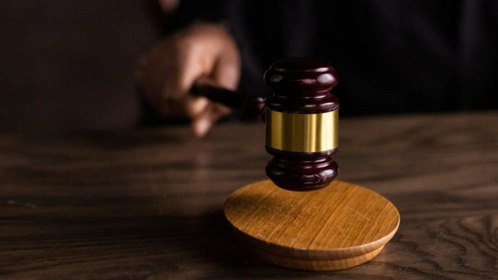 Wooden gavel striking a sound block on a courtroom desk.
