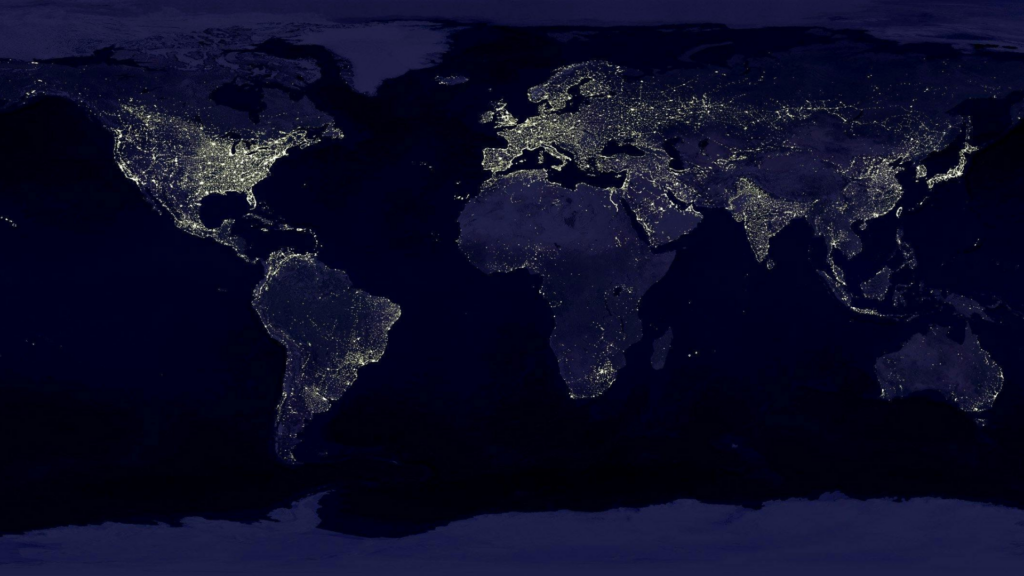 A composite satellite view of the Earth at night reveals the glow of city lights, highlighting densely populated and highly developed regions across the continents.