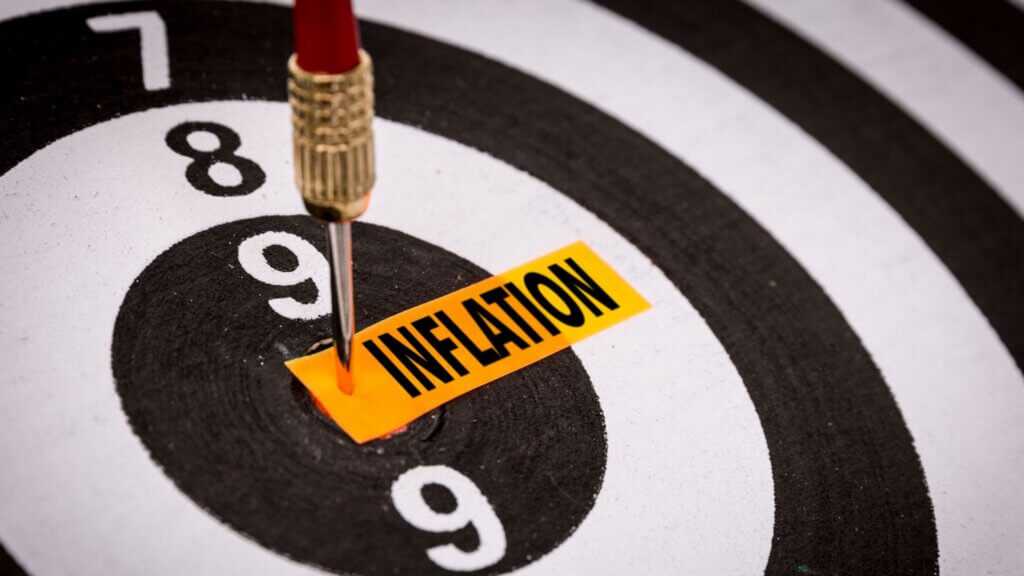 A dart strikes the center of a dartboard marked with the word 'INFLATION'.