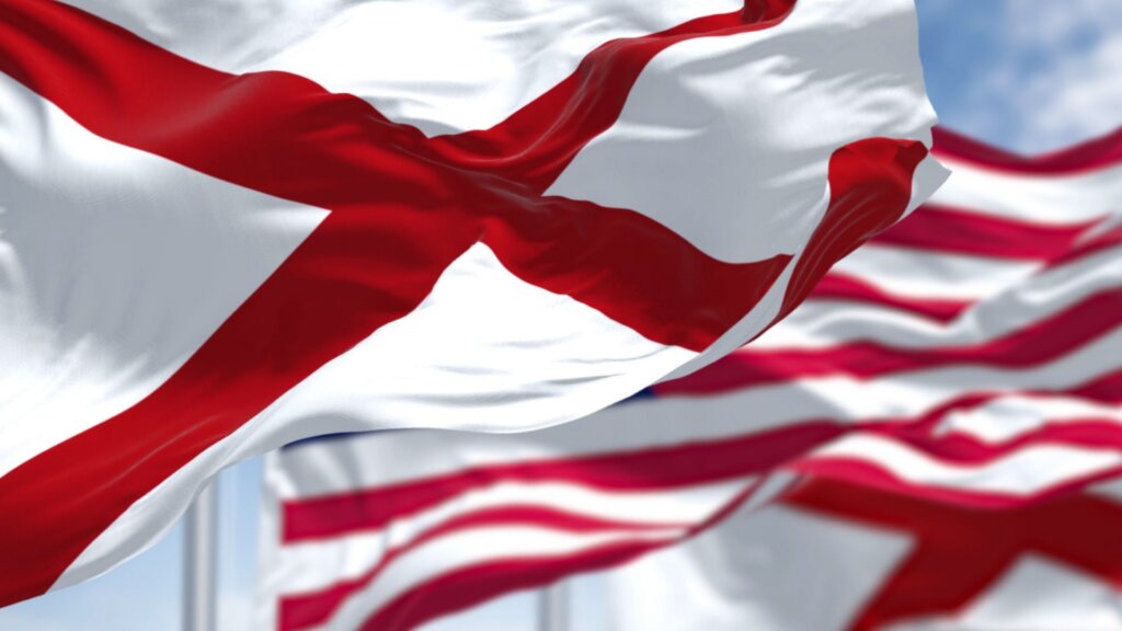 The flags of the Alabama state and United States of America waving in the wind.