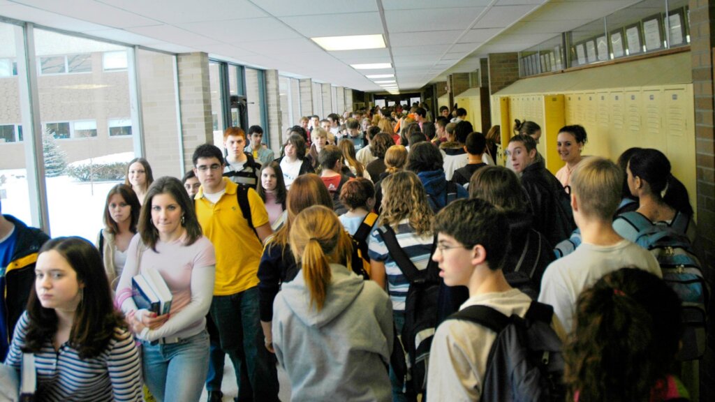Students walking through a crowded public school hallway between classes.