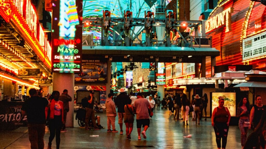 Crowds walking through Fremont Street Experience under glowing neon signs at night.