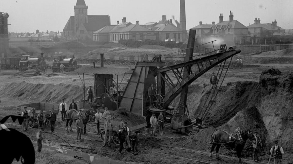 Archival black and white photograph of a 19th century railway construction site with workers and machinery.