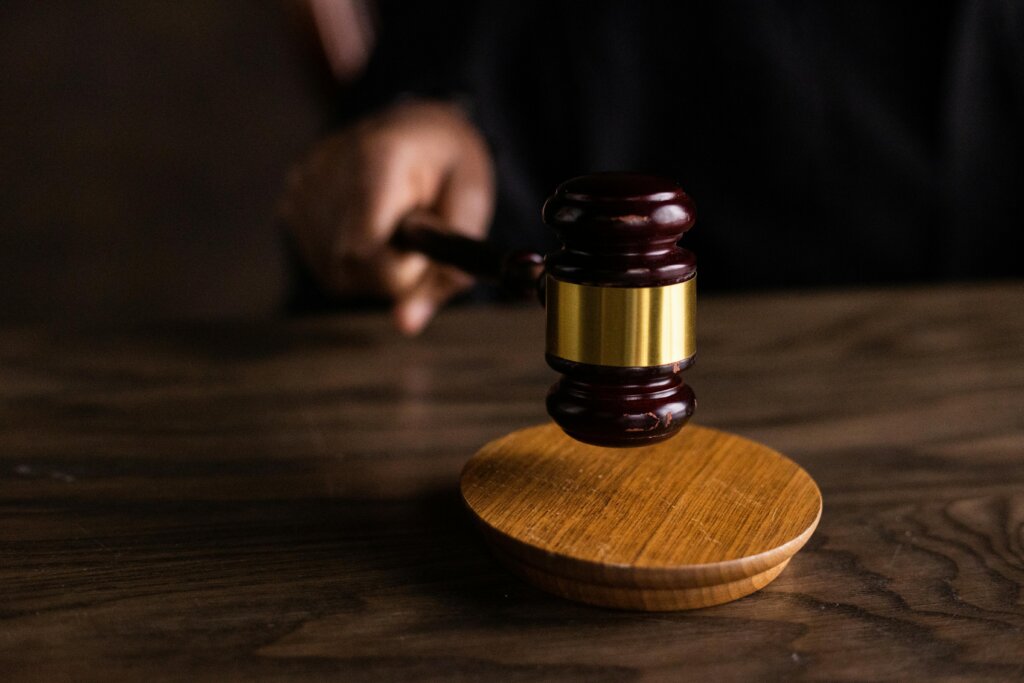 Judge’s gavel striking sound block on a wooden desk during court proceedings.