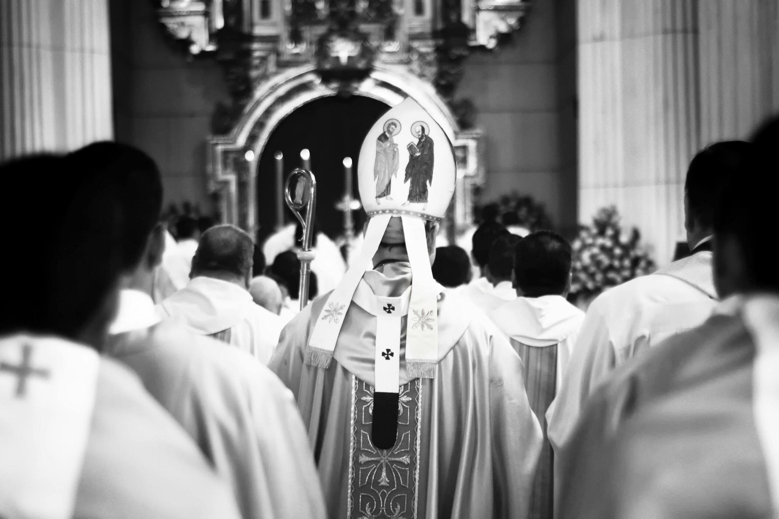 Catholic clergy seen from behind during a church service inside a cathedral.