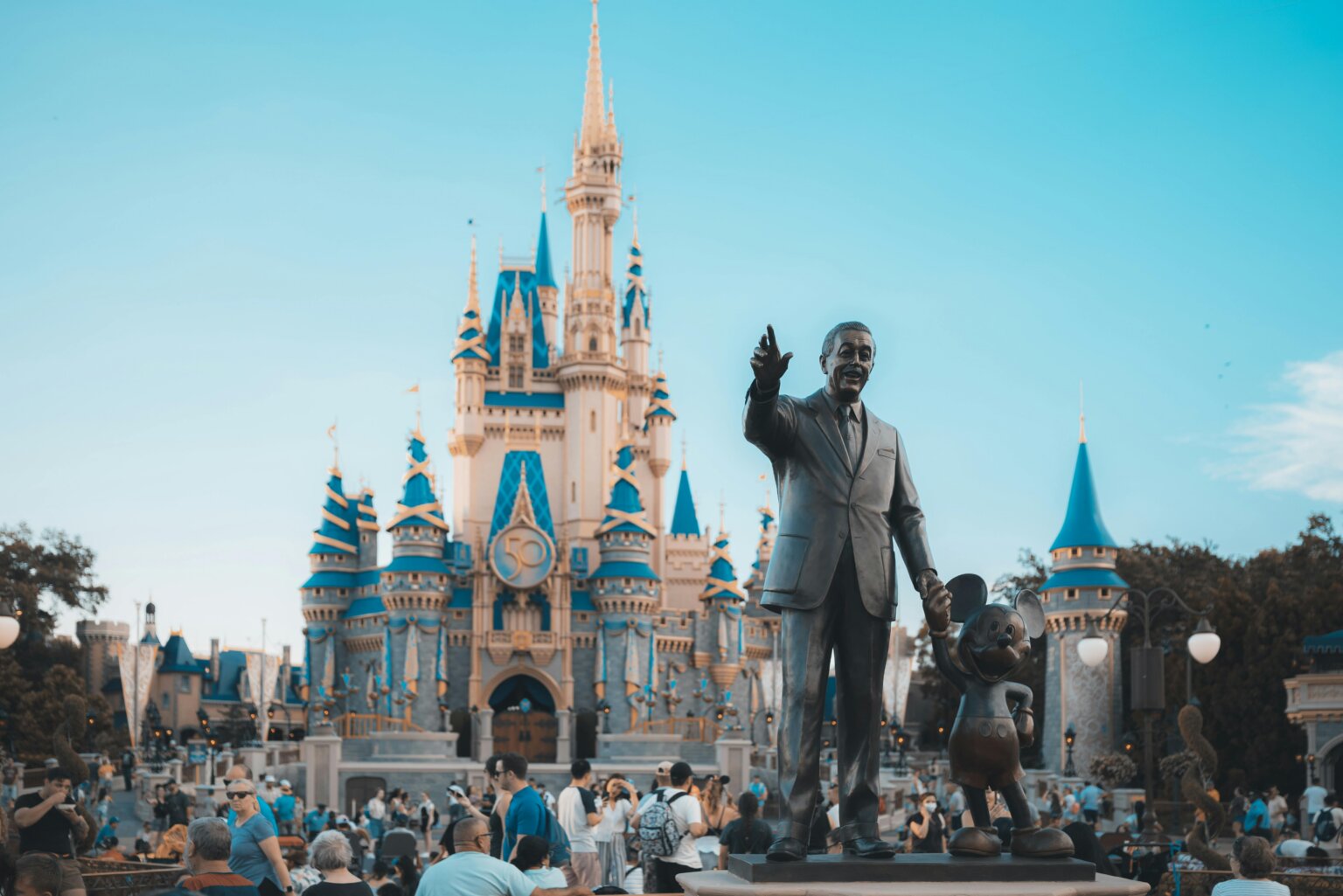 Statue of Walt Disney and Mickey Mouse in front of Cinderella Castle at Disney theme park.