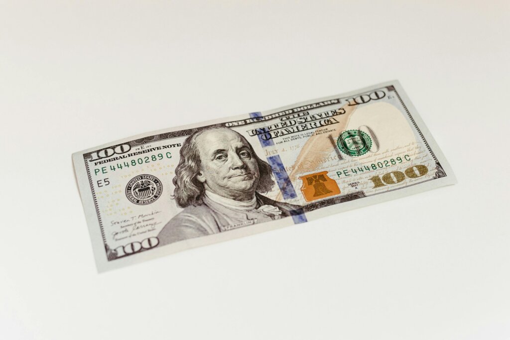 US $100 bill featuring Benjamin Franklin displayed on a plain background.
