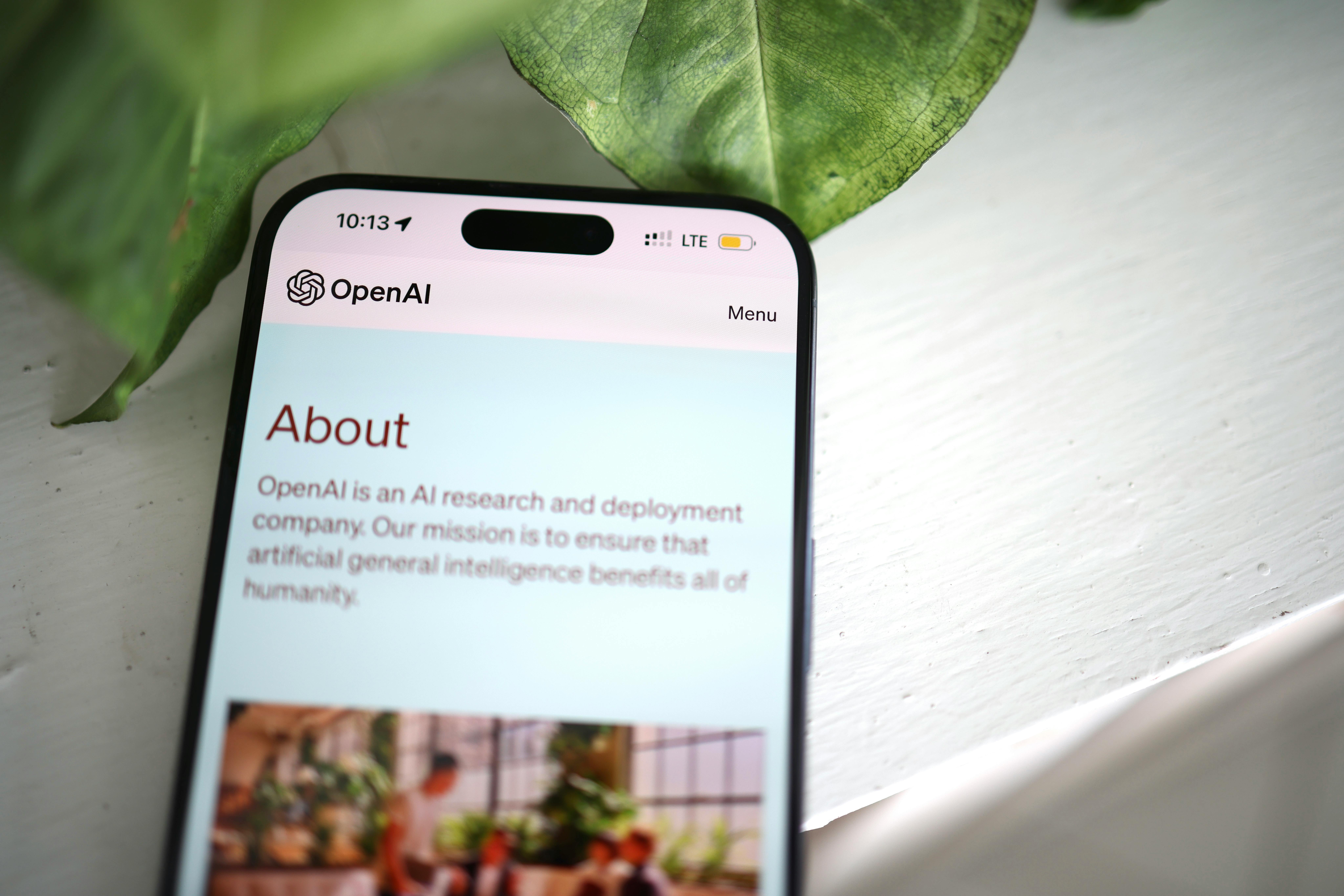 Smartphone displaying OpenAI About page with text describing its AI mission on screen.
