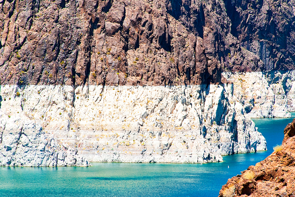 Lake Mead shoreline showing steep rock face with visible white bathtub ring marking low water levels.