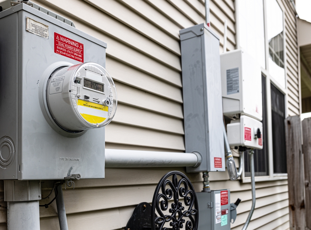Electric utility meter mounted on exterior house wall