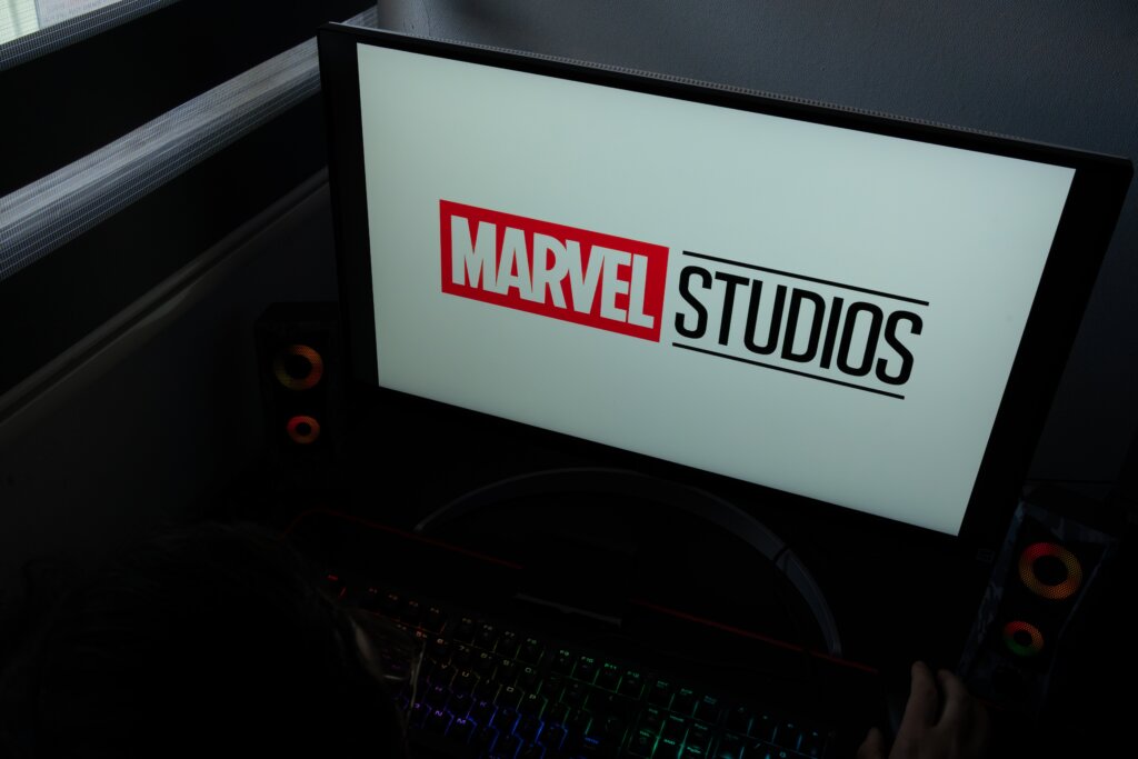Computer monitor displaying Marvel Studios logo on screen above a desk with keyboard and speakers.