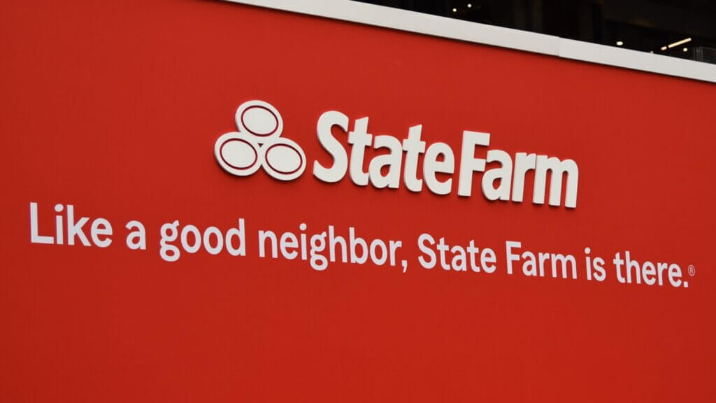 Red wall with State Farm logo and slogan reading "Like a good neighbor, State Farm is there." displayed prominently as part of insurance branding.
