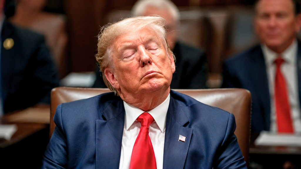 A close-up portrait of Donald Trump looking exhausted with his eyes closed and his head slightly tilted back while seated in a high-backed brown leather chair; he is wearing a dark blue suit and a bright red tie, capturing a candid moment of fatigue during a trial recess.
