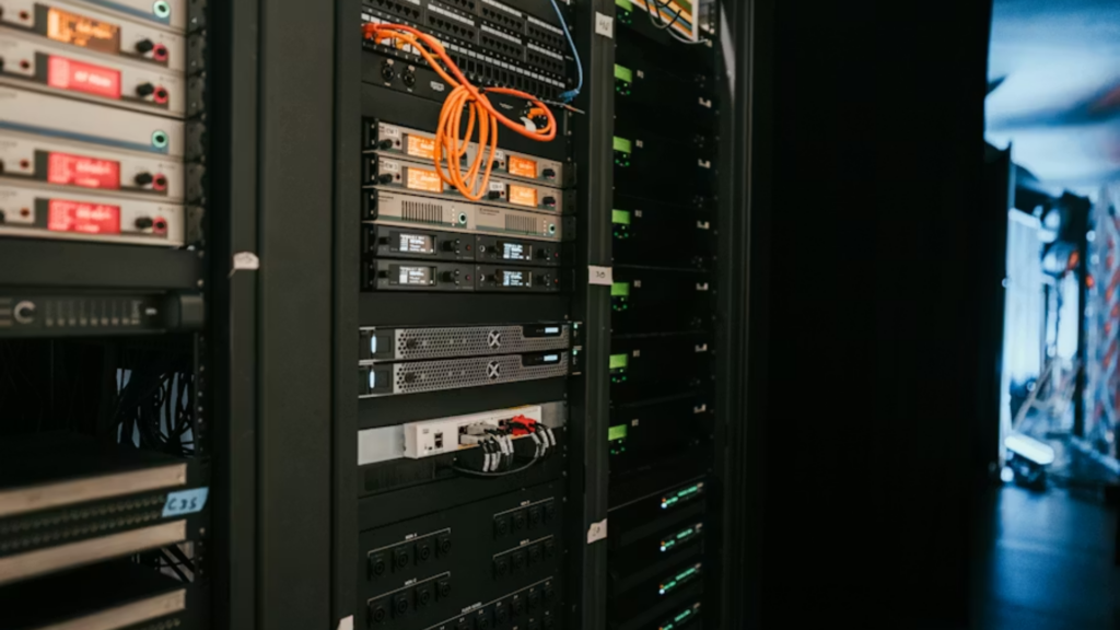A close-up, perspective shot of a modern data center server rack packed with sleek networking hardware, blinking orange indicators, and neatly organized cords, symbolizing Meta's massive infrastructure spending.