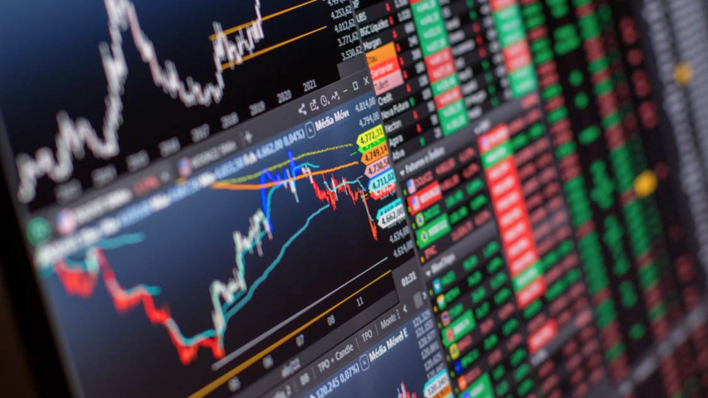 A close-up, angled view of a computer screen displaying complex stock market charts, candlestick graphs, and numerical data.