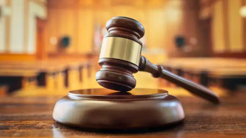 A shallow-focus close-up of a wooden judicial gavel resting on its sound block on a courtroom desk.